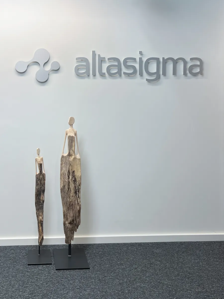 AltaSigma logo on the office wall with two wooden sculptures in the entrance area